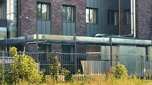 Modern dark red brick factory with steel air ducts on the facade.