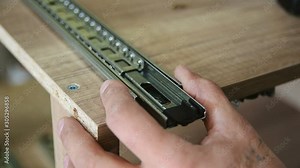 Assembling furniture, installing guides for drawers on furniture panels close-up.