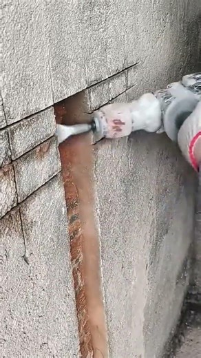 cutting a long narrow groove in a grey concrete wall surface using a professional electric grinder