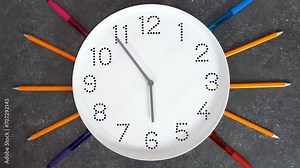 6 o'clock. Study or business time. Clock with white clock face on dark background with pencils, pens. Timelapse. Concept of study, work, deadline, schedule. Time management.
