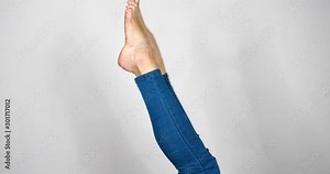 A Pair of Upside Down Woman's Legs Wearing Tight Fitting Blue Jeans Stretching and Waving Isolated on White
