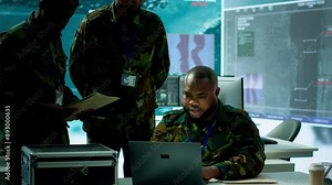 Military personnel in a modern command center handle critical information, collecting live surveillance data to maintain security protocols. Team of army crew working on reconnaissance. Camera A.