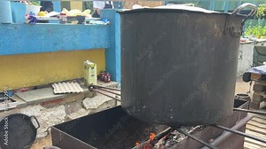 an old pot on the fire Old-style cooking with a large pot on an open fire. Black large iron pot traditional cooking on log wooden fire with visible flames and smoke
