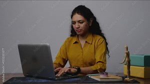 South Asian model typing on her laptop, then pressing a button and smiling While clossing the screen