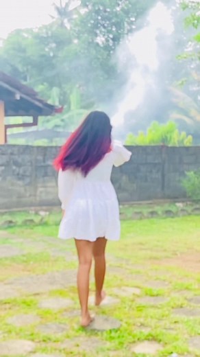 Woman in White Dress Walking Through a Lush Garden