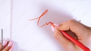 Closeup of calligrapher hands writes word LOVE on white paper. Inscribing ornamental decorated letters. Calligraphy, graphic design, lettering, handwriting, creation concept. 4k.