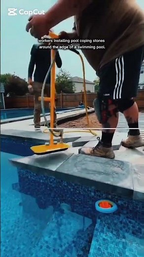 installing pool coping stones around the edge of a swimming pool.
