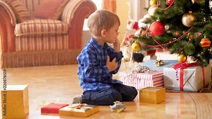 4k footage of upset little boy sitting under Christmas tree and crying because of unwanted present from Santa