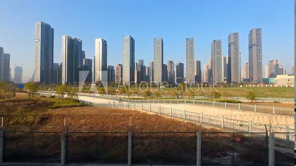 View through window from train travels on a nice day. Trains departing from a railway station passing over modern buildings and farm land in China, 4k real time footage.