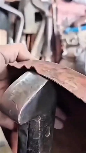 shaping rusty copper metal sheet using a heavy metal hammer on an anvil for traditional craftwork