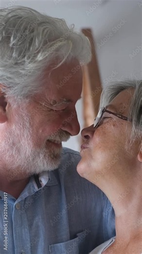 Happy mature couple in love kissing, laughing, and showing affection in a tender moment at home