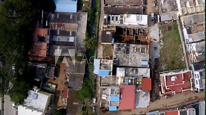 mix of residential buildings, narrow streets, and some green spaces. The buildings have varied roof designs and colors, and there’s a visible contrast between built-up areas and open spaces.
