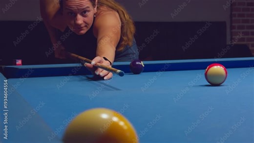 Woman Leaning Over Pool Table Aiming Cue At Cue Ball With Intense Focus In Dark Billiard Club Interior