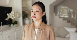 Close up Asian woman makes inhales exhales standing alone in living room with eyes closed, breathing fresh air inside, recover inner calmness after situation, reduces stress, take moment to revitalize