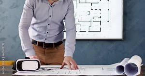 Engineer measures length on plan using ruler and draws line with lead pencil. Employee draws on draft while virtual reality glasses lies near on table