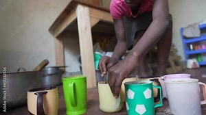 Black hands preparing breakfast at African orphanage. Mixing milk with porridge. NGO program for development. Africa 4K.