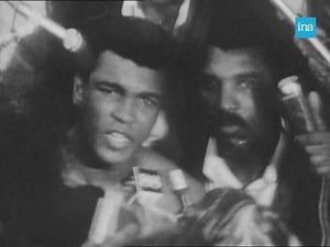 COMBAT DU SIÈCLE.🥊 Le 30 octobre 1974 au Zaïre, ambiance de fête pour recevoir le match de boxe du siècle. Cassius Marcellus Clay, plus connu sous le nom de Mohamed Ali, remporte le titre de champion du monde contre Georges Foreman. | INA