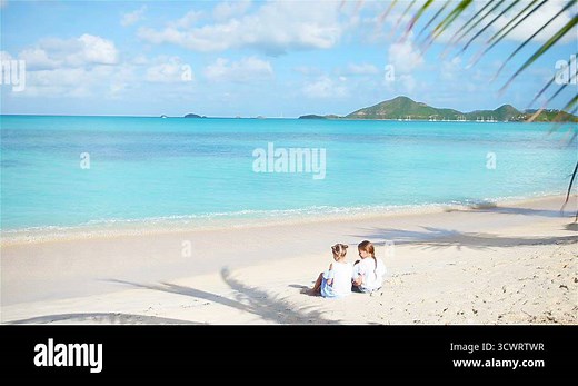 Adorable little girls playing with sand on the beach. Kids sitting on the seashore and making a sandcastle