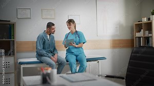 Doctor Consultation Office: Sitting on Exam Table Male Patient Listens to Experienced Head Nurse who Uses Digital Tablet Computer to Show, Explain His Analysis Results, Prescribe Medicine