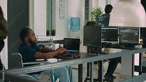 Software app coder in wheelchair writing programming language on computer, using big data and firewall server. System engineer with physical impairment in disability friendly agency.