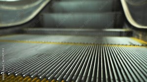Close up of the moving down empty escalator steps with grooves and yellow safety lines.