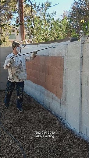Spray painting a cinder block wall.