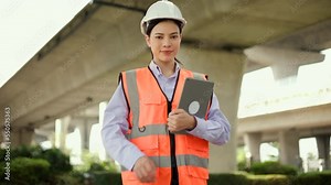 Confident woman Engineer or architect looking camera with white safety helmet in construction site. Supervisor Engineer female working at construction project. Civil engineering concept.