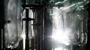 Production Line of Mineral Water and Carbonated Beverages in Plastic Bottles. Industrial Robotic Mechanism for Filling Plastic Bottles. Moving and Rotating of Plastic Bottles Closeup.