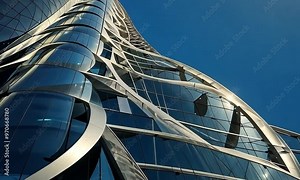 Futuristic skyscraper with a twisting, spiraling design rising against a bright blue sky