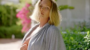 Blond Woman Wearing Open Grey Robe Revealing Bare Skin Beneath Looking Startled or Surprised at the Camera in Back Yard Garden