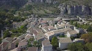 Low descending aerial over ancient village rooftops to Ardeche River