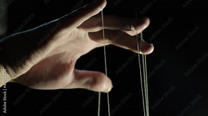 The puppeteer's hand controls the puppets on strings. Manipulation concept