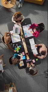 Vertical Screen Top Down View: Innovative Teamwork at Office Table. Diverse Professionals Collaborate Using Laptops and Tablets, Strategizing and Brainstorming For Creative Business Problem Solving