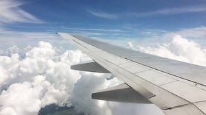 View from the window of a commercial airliner traveling above clouds and landing from a high altitude.