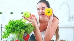 Beauty young funny woman holding fresh vegetables and smiling in her kitchen at home. Healthy eating concept. 4K UHD video footage. Ultra high definition 3840X2160