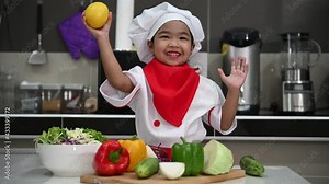 Cute asian girl wear chef uniform with a lot of vegatable on the table in the kitchen room,Make food for eat dinner,Funny time for kids