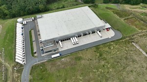 Loading bay, truck parking lot, industrial building, logistics - aerial view - tracking shot