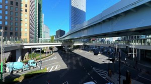 Modern urban road intersection in Tokyo with overpass, tall buildings, and clear blue skies