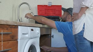Work plumbing in the kitchen. The woman controls the work of the plumber.