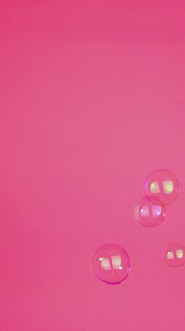 Bubbles floating on a pink background - Free Stock Video