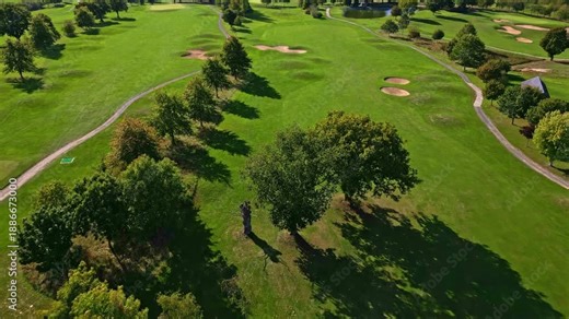 Angled aerial of golf course fairways trees and paths in lush green landscape, sport backdrop, nobody empty