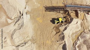 Single wheel loader working at sand pit. Sorting process at sand quarry. Top down aerial following shot.
