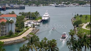 View of yachts, boats, and condos at Atlantis resort marina. Boats head to sea through harbor channel.