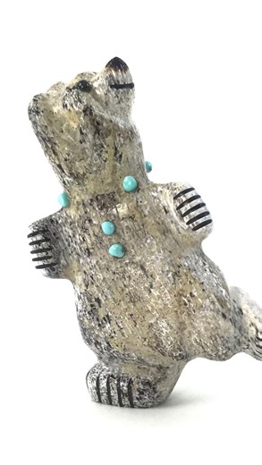 This small stylized bear fetish from Zuni Pueblo artist Claudia Peina is a stunning representation of an ancient art. Handcrafted from elk antler, the carved piece is ivory-hued with a beautiful black mottling and depicts a bear figure balancing on one foot with its eyes raised towards the sky. 🐻✨ Zuni bear fetishes are a symbol of strength, courage, healing and protection, making this piece a meaningful addition to your Native American art collection. | Indian Pueblo Store