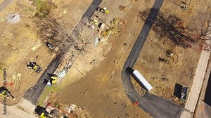 Fly over heavy construction machines working on land improvements for manufactured home site, floating slab structural in Upstate New York. Aerial trailer park concrete road, sewer infrastructure