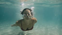 Underwater girl swimming in the crystal clear water, wearing red...