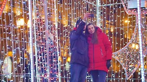 Young fun couple are doing selfie in the night city on a background of bright colorful garlands in a gift box