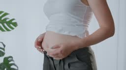 Woman's hands holding fat belly and can't fit in her pants. The diet...