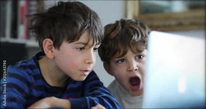Casual authentic children looking at laptop computer screen. Candid kids starring at internet content2
