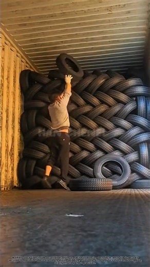 This worker neatly arranges tires inside a container.